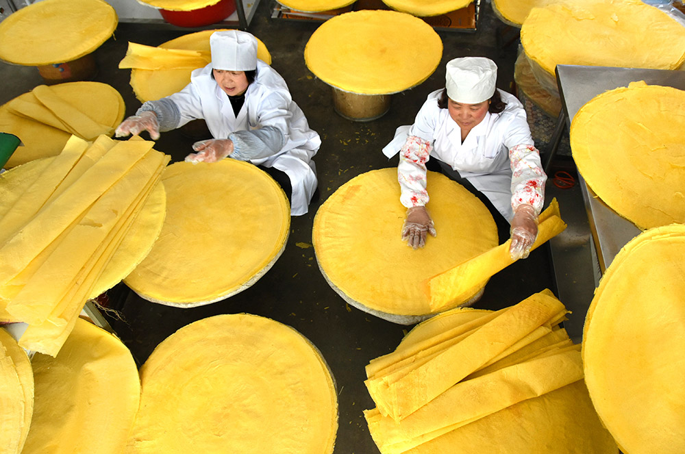 山东省沂源县历山街道吴家官庄村的农家妇女在加工煎饼（3月6日摄）。