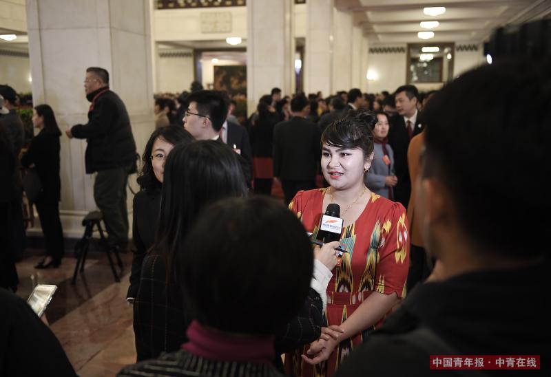3月20日上午，北京人民大会堂，新疆维吾尔自治区于田县兰干乡民政社会保障事务所干部如克亚木·麦提赛地在“代表通道”接受采访后，被记者包围。中国青年报·中青在线记者 王婷舒/摄