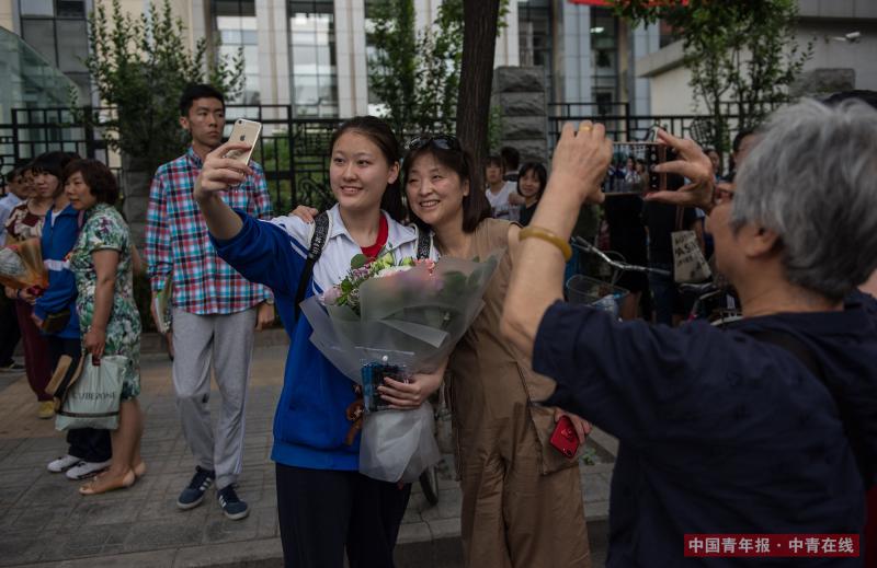 6月8日下午，北京东直门中学高考考点外，高考结束后，考生家长为孩子献上鲜花并自拍留念，考生的姥姥在一侧为母女二人拍照。中国青年报·中青在线记者 王婷舒/摄