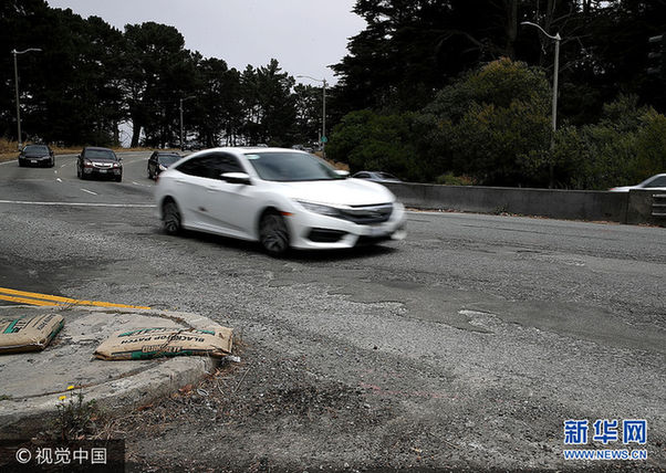 当地时间2017年7月12日，美国加州奥克兰，据报道，旧金山、奥克兰和其他四座加州城市的道路是全美道路状况最差的城市，司机因为坑洼不平等道路问题，每年平均花费978美元修车。***_***SAN FRANCISCO, CA - JULY 12: A car drives over cracked and uneven asphalt on July 12, 2017 in San Francisco, California. According to a report by WalletHub, roads in San Francisco, Oakland and four other California cities are the worst in the United States. Drivers in San Francisco and Oakland pay an estimated $978 per year to repair vehicle damage from driving on roads with potholes and uneven pavement. (Photo by Justin Sullivan/Getty Images)