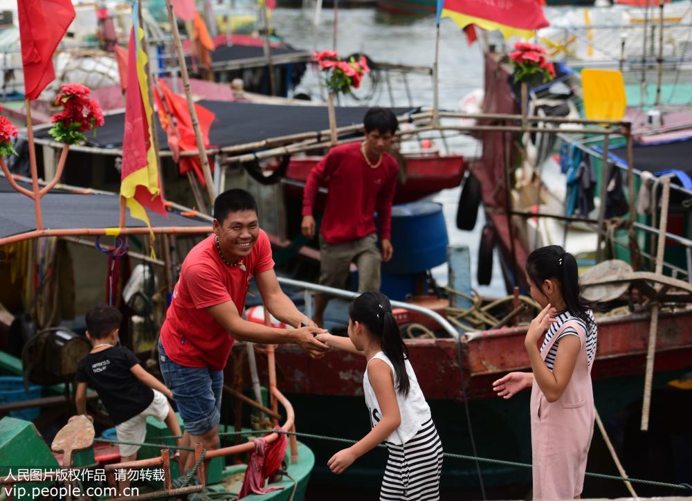 8月16日，海南省琼海市潭门港，一名渔民与孩子们牵手告别。
