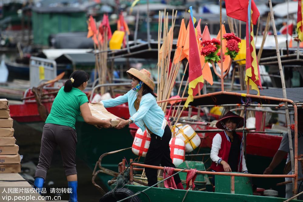 8月16日，海南省琼海市潭门港，渔民正往渔船上搬运物资。
