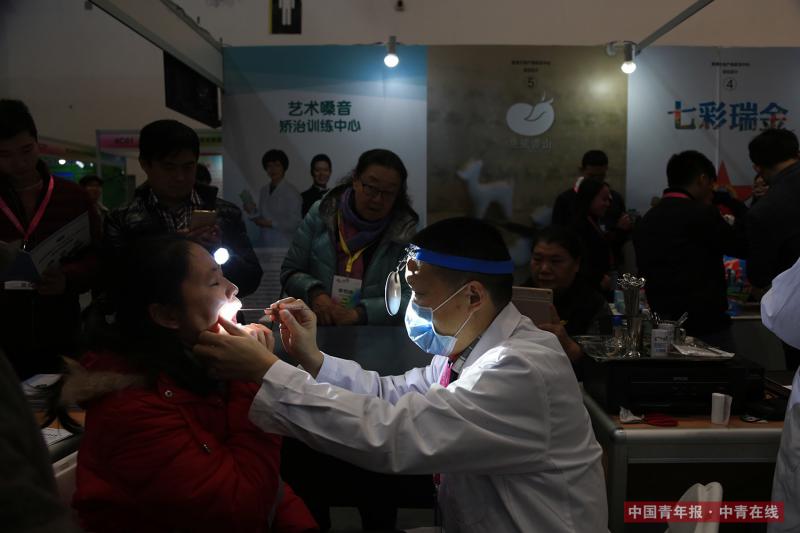 12月9日，一名参展工作人员为参观者检查和矫正嗓音。中国青年报·中青在线记者 赵迪/摄