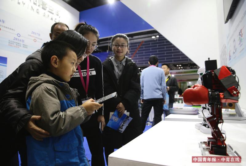 12月9日，西北工业大学飞天创客空间展台，一位母亲带着孩子操作小机器人。中国青年报·中青在线记者 陈剑/摄