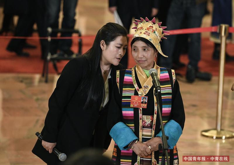 3月11日下午，北京人民大会堂，西藏自治区隆子县玉麦乡玉麦村村务监督委员会主任卓嘎（右）在翻译的协助下在“代表通道”接受记者采访。 中国青年报·中青在线记者 王婷舒/摄
