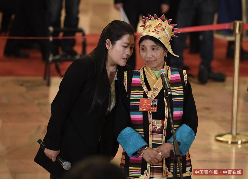 3月11日，北京人民大会堂，西藏自治区隆子县玉麦乡玉麦村村务监督委员会主任卓嘎（右）在翻译的协助下在“代表通道”接受记者采访。中国青年报·中青在线记者 王婷舒/摄