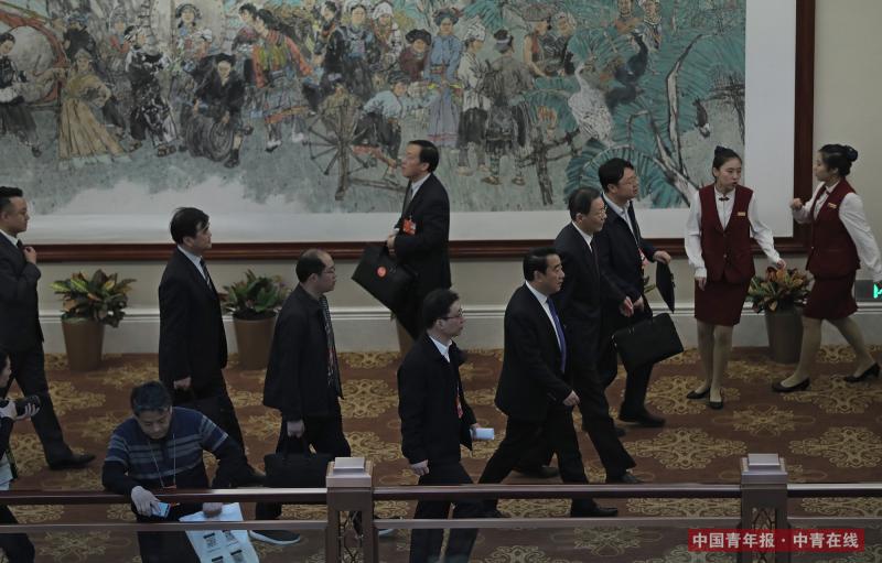 3月14日，北京国二招宾馆，江苏代表团全体会议后，几位代表和工作人员经过一幅“民族一家亲”主题的壁画。中国青年报·中青在线记者 赵青/摄