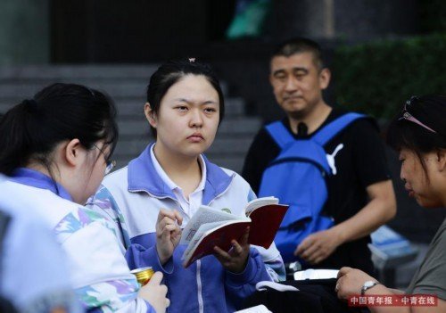 6月7日，北京陈经纶中学高考考点前，考生在进入考场前抓紧时间复习。中国青年报·中青在线记者 陈剑/摄