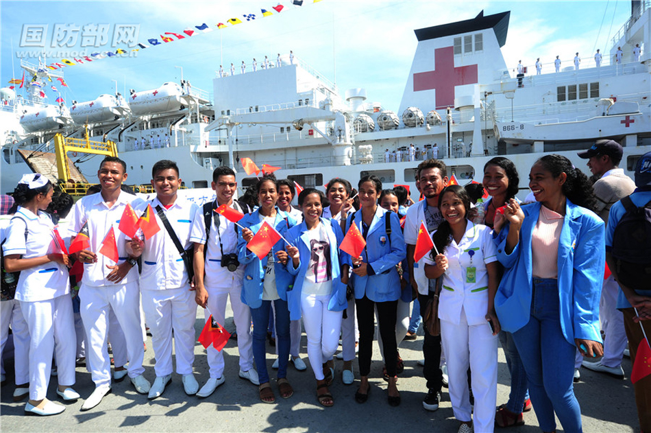 12月14日，在东帝汶帝力港码头，东帝汶民众和学生挥动中国与东帝汶两国国旗欢迎中国海军和平方舟医院船首次到访。 江山 摄