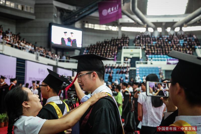 7月2日上午，北京，清华大学2017年本科生毕业典礼暨学位授予仪式现场，一名老师为学生整理衣装。中国青年报·中青在线记者 赵迪/摄