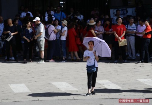 6月7日，北京陈经纶中学高考考点前，一位家长撑着伞在烈日下等候。近日，北京经历高温天气，高考第一天最高气温达 33℃。中国青年报·中青在线记者 陈剑/摄