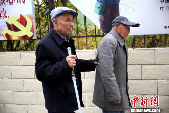 图为两位老人出去散步，刘龙一直抓着崔裕海腰侧的衣服。　张海雯摄