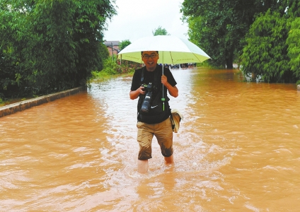 张磊在洪水中采访。资料图片