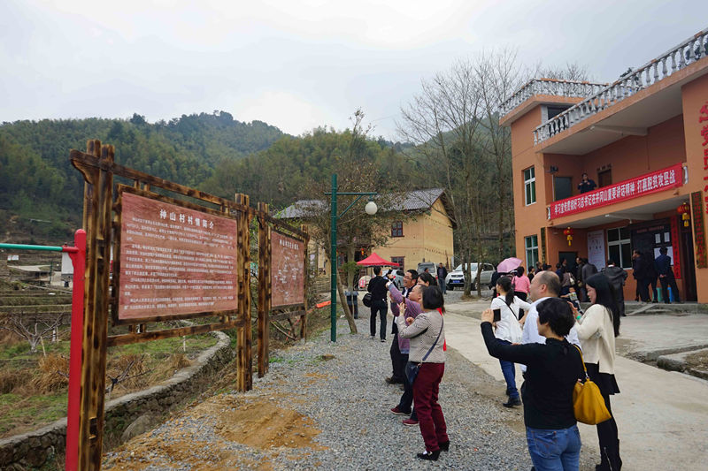 游客在江西井冈山写有“神山村村情简介”的木牌前驻足拍照（2016年3月7日摄）。新华社记者 赖星 摄 