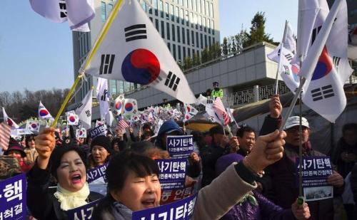 朴槿惠的支持者在她抵达首尔中央地方检察厅时挥舞着国旗，高喊支持她的口号。（图片来源：法新社）