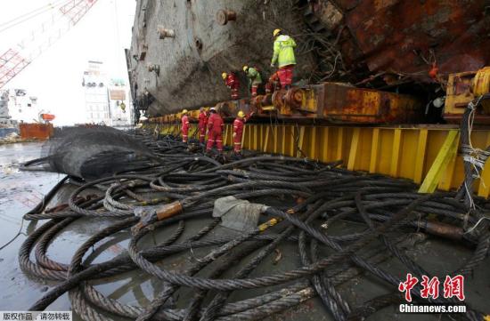 当地时间3月27日，韩国珍岛工人正在移除“世越号”船体上的电线。日前沉没近3年的韩国“世越号”船体已经被抬出水面。
