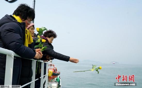 当地时间2017年3月28日，韩国珍岛，民众悼念“世越”号遇难者。为将“世越”号沉船运至木浦新港，打捞组正加速进行排水和除油工作。