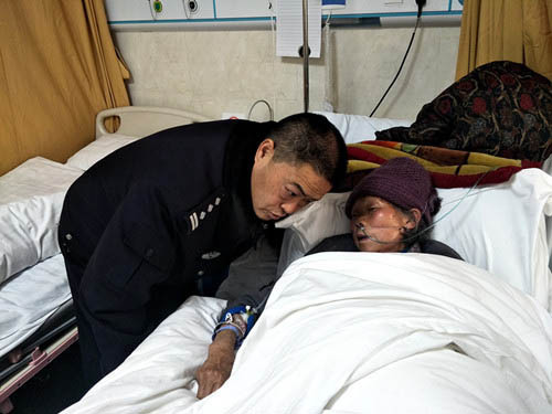 图为龙文进在医院照顾患病的潘发芬老人。图片来源：贵州省文明办