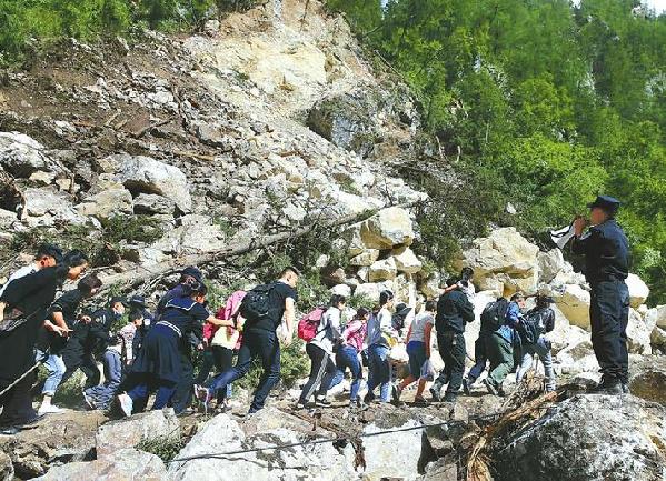 8月9日，公安特警在九寨沟灾区一处悬崖边冒着飞石的危险设立观察哨，帮助游客疏散转移。