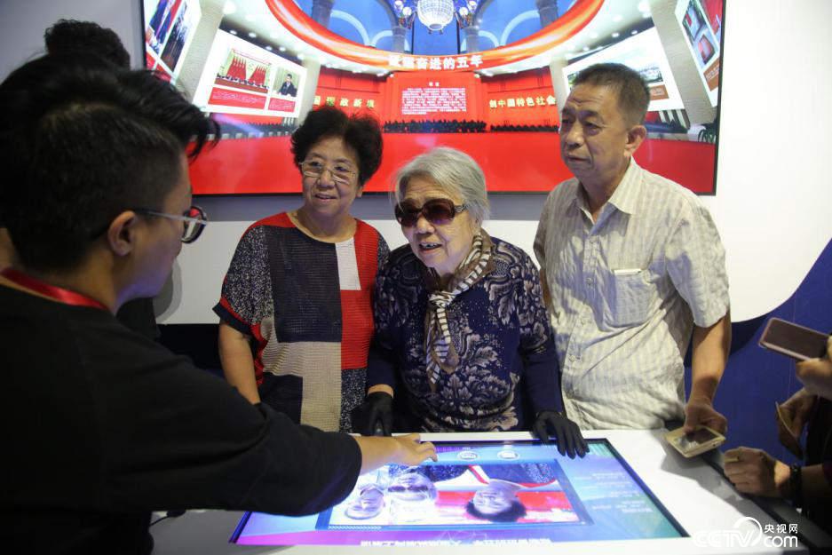 89岁老人王志强与家人在电子屏前为喜爱的展区点赞