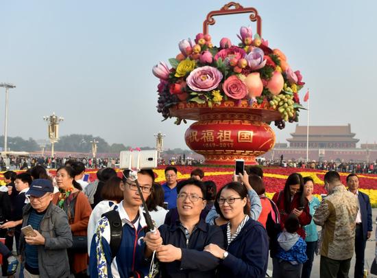 10月1日，游客在北京天安门广场“祝福祖国”花篮前留影。 新华社记者 罗晓光 摄
