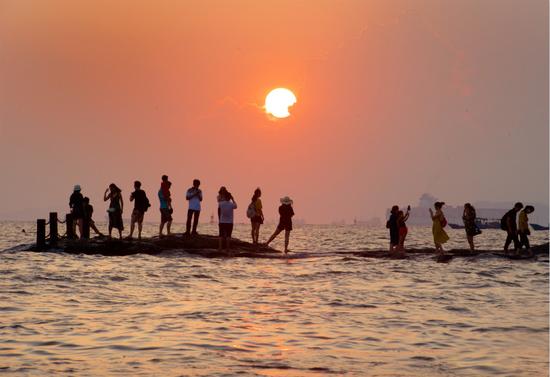 10月1日，游客在日落时分的厦门白城沙滩海边游玩。新华社记者 姜克红 摄