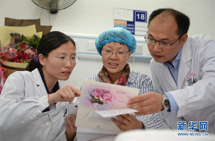 郭璐萍（中）在观看即将援非的医疗队成员为她创作的诗歌和集体签名卡片。