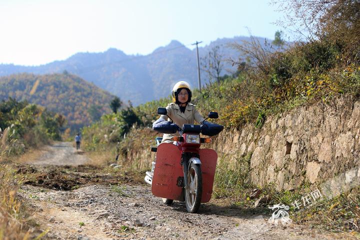 严克美骑着男士摩托走访村民。记者-李文科摄.jpg