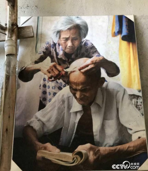 图为童汉芳母亲给正在阅读的父亲修剪白发