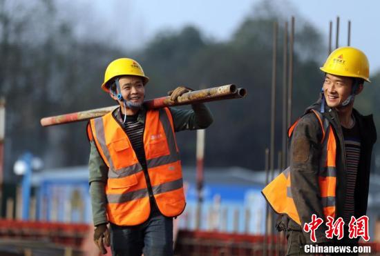 建筑工人倪文军(左)扛着铁管准备搭建脚手架.