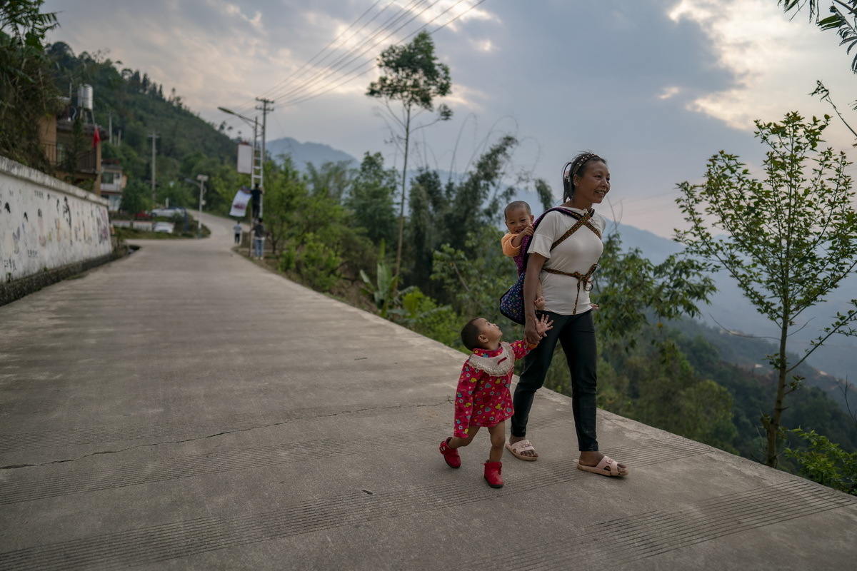 一名妇女领着孩子走在回家的路上（3月26日摄）。