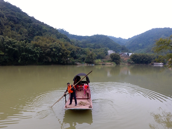 倪华成在广西岑溪市波塘镇杨亦村黄华河上摆渡接送孩子(2月27日摄)