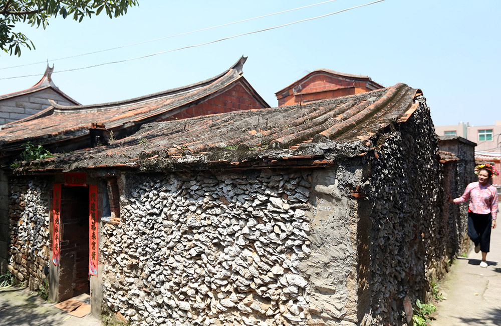4月24日,在福建省泉州市丰泽区蟳埔村,一名游客参观一处蚝壳厝.