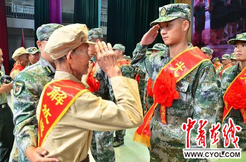 参加过解放战争的老兵罗发家为新入伍战士披红戴花,新兵向功臣敬礼