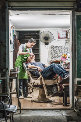 武汉的老街上,老式理发店里,老师傅正给年轻的顾客刮脸